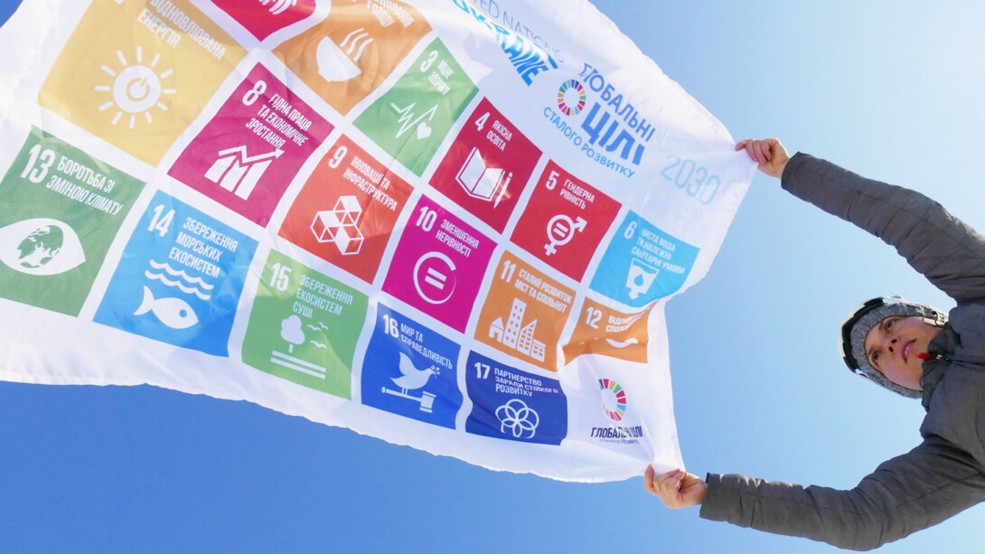 A-woman-holds-a-flag-of-the-SDG-of-the-UN