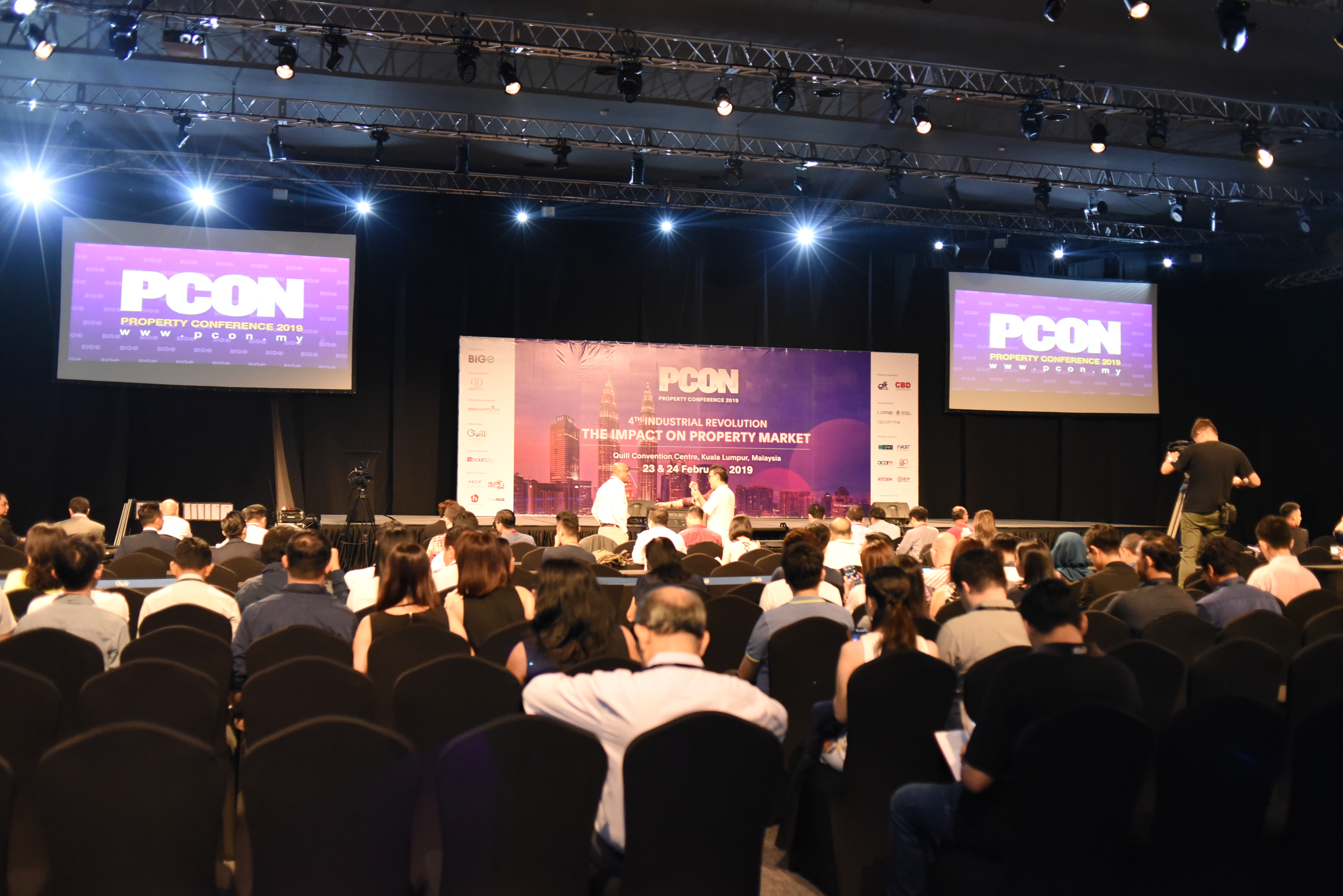 A speaker presenting a diagram on a large screen to the audience.